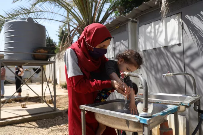 Lebanon. A woman helps her child wash her hands.