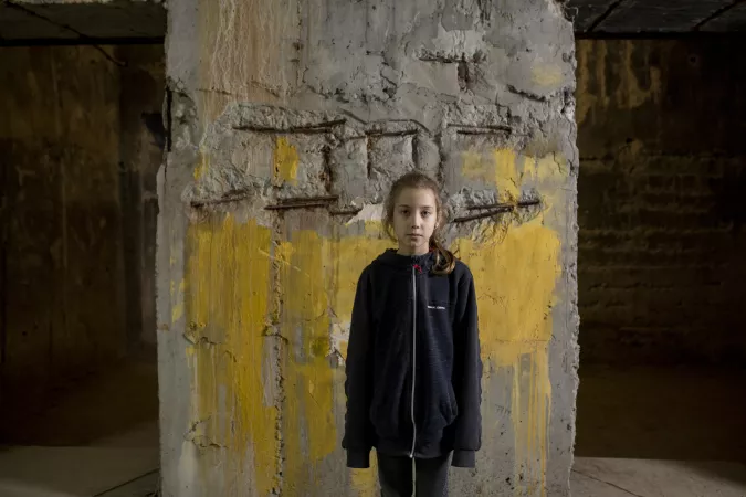 Une petite fille se tient devant un mur