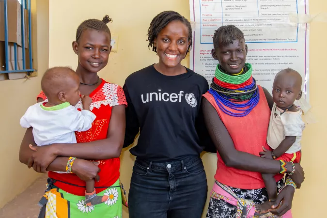 Climate activist Vanessa Nakate stands between to mothers and their babies in Turkana County, Kenya.