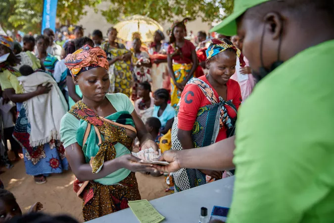 En Mozambique, una madre beneficiaria recibe de manos del t&eacute;cnico del gobierno el dinero del subsidio entregado a los ni&ntilde;os de 0 a 2 a&ntilde;os.