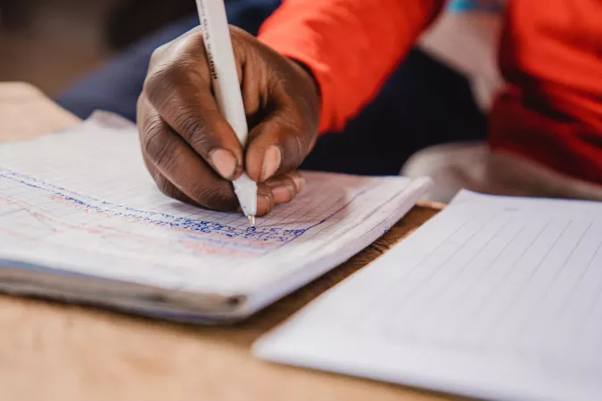 A close up image of a hand holding a pencil, writing.