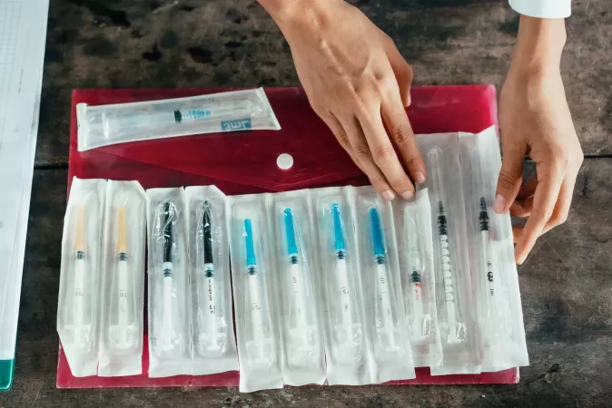 Two hands arranging vaccine syringes. 