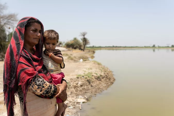 Pakistan. Benazi stands holding her daughter next to stagnant water that still remains more than six months after floods in Sindh Province.
