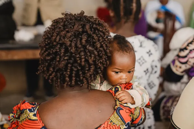 A mother holds her infant over her shoulder.