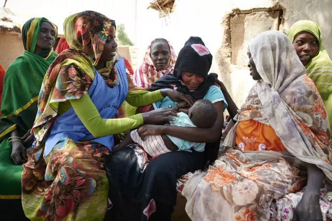 A mother breastfeeds her child, with support. 