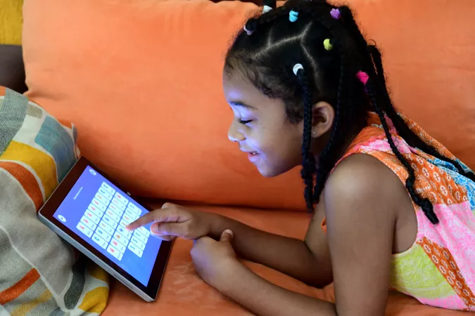 A seven-year-old girl in C&ocirc;te d'Ivoire studies at home on a tablet device in 2020.