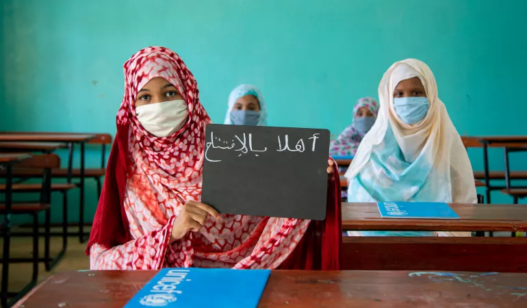 The young Fatimetou carries her slate with the inscription "I love school" written on it in arabic in front of her classmates.