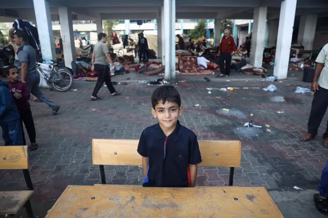 State of Palestine. A boy stands behind a school desk.