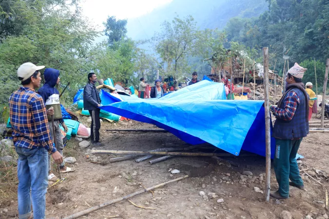 People set up a tarp for displaced families.