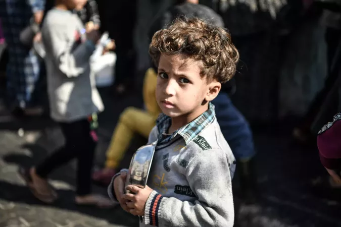 &Eacute;tat de Palestine. Un gar&ccedil;on attend son tour dans la foule pour recevoir un repas de la part d'un organisme de bienfaisance qui distribue de la nourriture gratuitement dans la ville de Rafah.