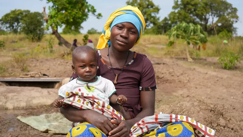 A mother holder her baby while sitting next to her fields in Falaba, southern Mali.