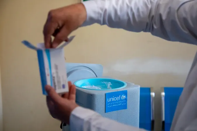 A vaccinator in health centre is packing vaccines into a carrier and preparing to travel .