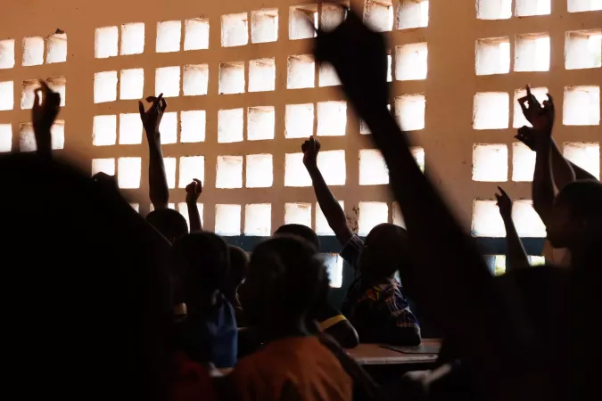 Children raising their bands in a classroom.