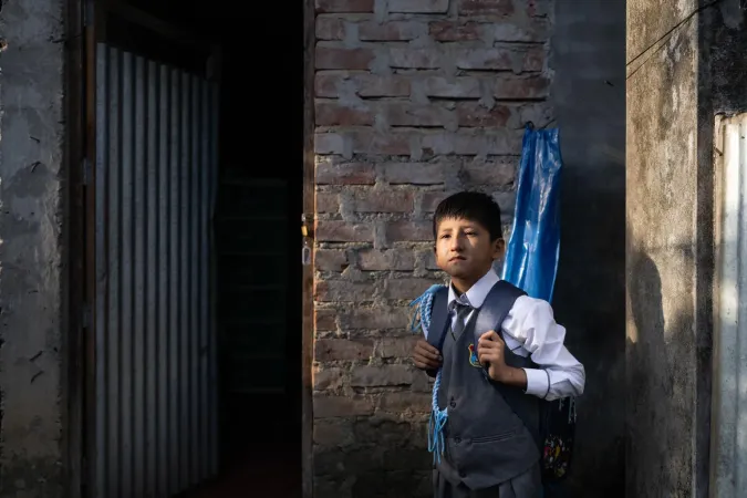 Boy in Peru stands outside his house before school. 