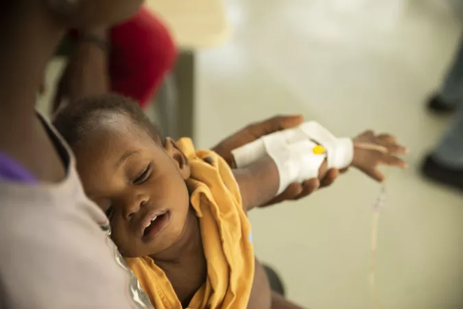 A young child with an IV taped to his hand sleeps on his bed as he suffers from cholera symptoms at Centres Gheskio in Port-au-Prince, Haiti, Friday, Oct. 14, 2022.