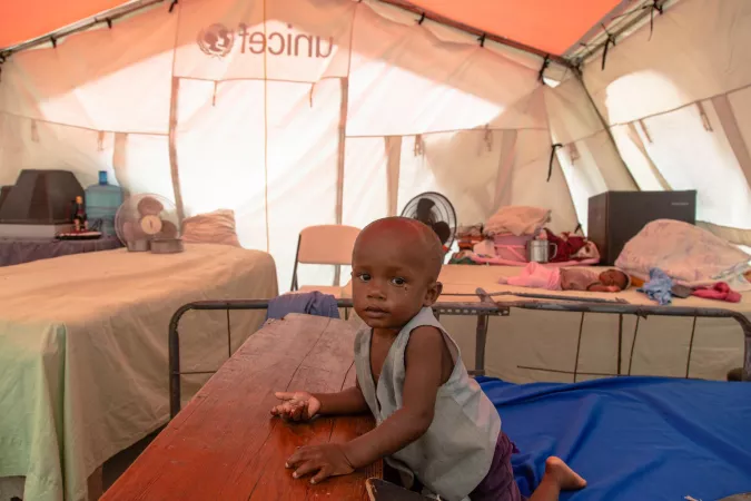 Karl, 15 months, sits in a UNICEF-supplied tent in the temporary shelters at Phillipe Guerrier High School in Les Cayes, Haiti on 17 August 2021