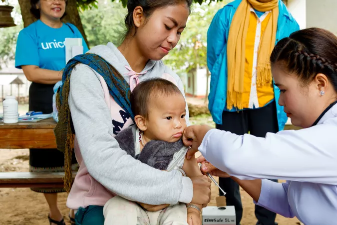 A woman holds a baby who is vaccinated, Laos