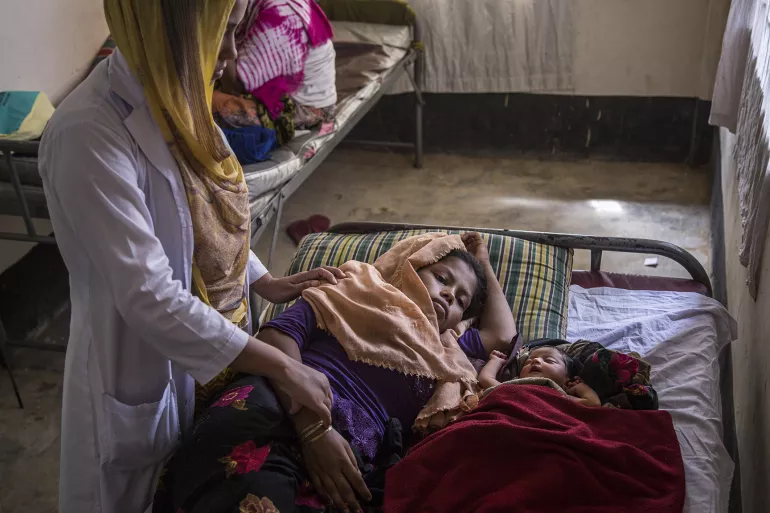 A midwife checks on exhausted new mother Hazera Begum, 18, who is recuperating next to her sleeping infant daughter, 3-day-old Kismat Ara, at the UNICEF-supported birthing centre in the Kutupalong camp for Rohingya refugees, in Cox&rsquo;s Bazar, Bangladesh. October 2017 