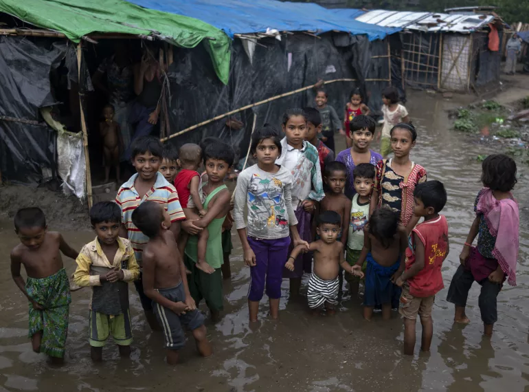 Rohingya refugee children wade through flood waters surrounding their families' shelters following an intense pre-monsoon wind and rain storm in Shamlapur Makeshift Settlement, Cox's Bazar district, Bangladesh on 20 May 2018.