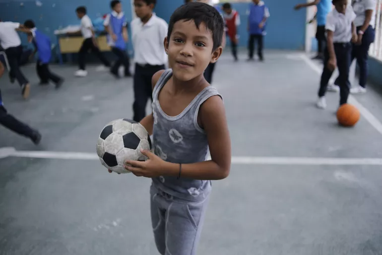 4 June 2019: A child playing on the roof of El Carmen school in Barrio Union, Petare, in the outskirts of Caracas, Venezuela. It is too dangerous to play outside and children head straight home as soon as they leave school. Even a basketball hoop right outside the school was removed to discourage children from hanging out outdoors.