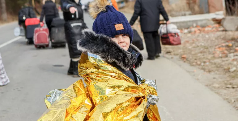 Une jeune fille regarde l'appareil photo alors qu'elle et d'autres personnes marchent le long d'u