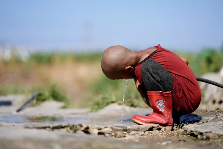 A Child drinking water from the only source in Hesbi Camp in Saida.