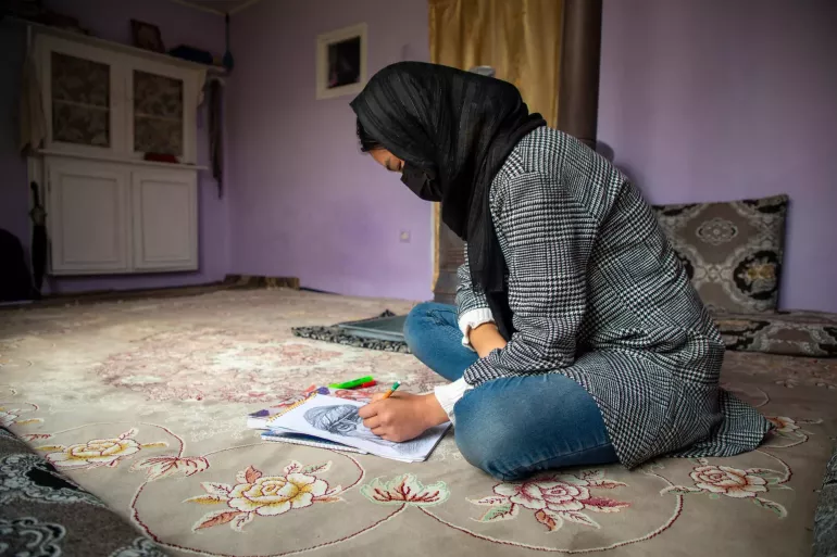 Une jeune fille dessine &agrave; la maison. 