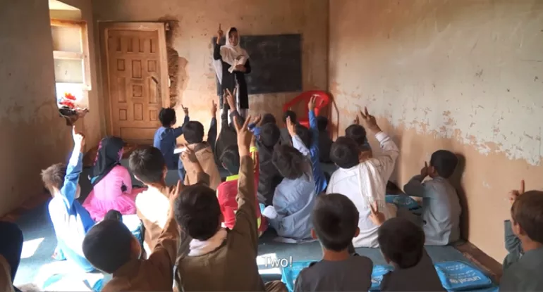 Female teacher in front of a classroom full of students in Afghanistan