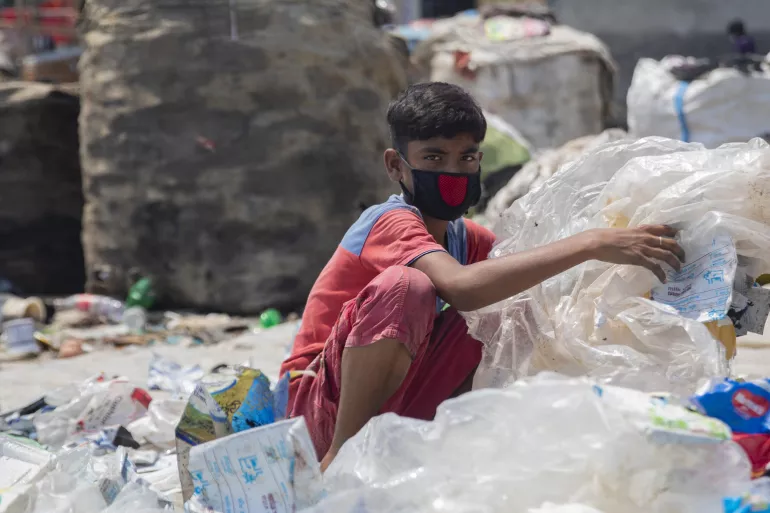 12-year-old Miajul sorts through hazardous plastic waste in Dhaka, Bangladesh, to support his family during the COVID-19 pandemic. 