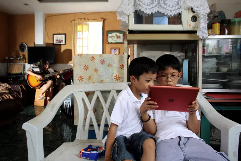 Two brothers look at an iPad in the Central Visayas city of Cebu, Philippines.