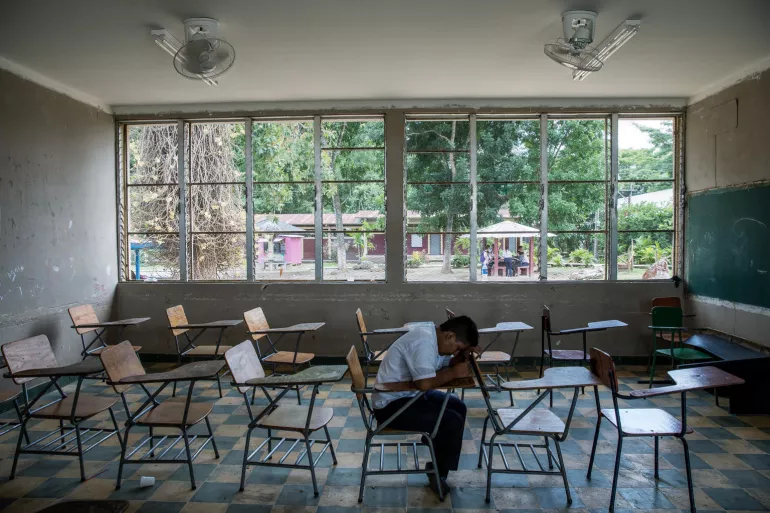 Un ni&ntilde;o sentado solo en un sal&oacute;n de clases, Honduras