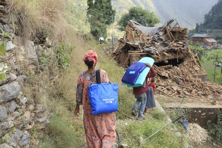 People walk among the rubble of their home destroyed by an earthquake.