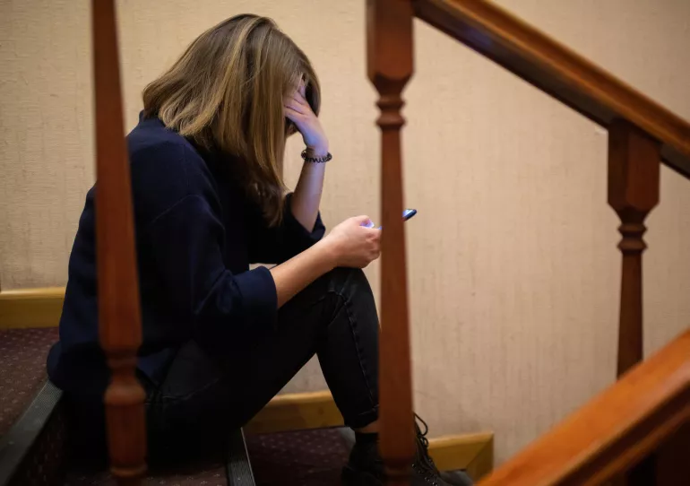 Une jeune fille assise sur des marches d'un escalier utilise son téléphone portable