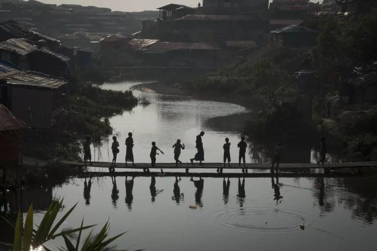 Un grupo de ni&ntilde;os refugiados rohingya se re&uacute;nen al atardecer en un puente de bamb&uacute; en el asentamiento improvisado de Kutupalong, en el distrito de Cox&rsquo;s Bazar, Bangladesh, jueves 11 de enero de 2018