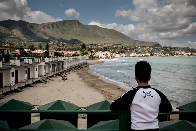 A boy who is an unaccompanied minor looks across the beach in Trabia, Italy, on May 14, 2016. He lives at Rainbow, a government administered centre for unaccompanied boys that provides shelter, food, education and legal help for unaccompanied asylum seekers in Trabia, Sicily. Of the 150,000 migrants and refugees who arrived in Italy in 2015, the vast majority of people are coming from West Africa.
