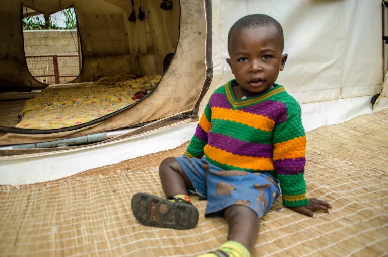 Rwanda. A child sits outside a mobile childcare tent.