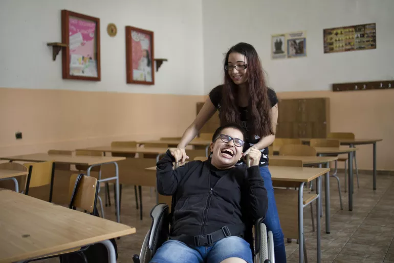 Maria Alexandrova and her best friend, Vanessa Georgieva, in a classroom of &ldquo;Kozma Tritchkov&rdquo; Secondary School in Vratsa, Bulgaria. Maria, 17 years old and living with cerebral palsy, is an advocate for other adolescents with disabilities in Bulgaria.