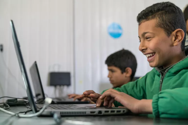 A child learns on a computer in a caravan.