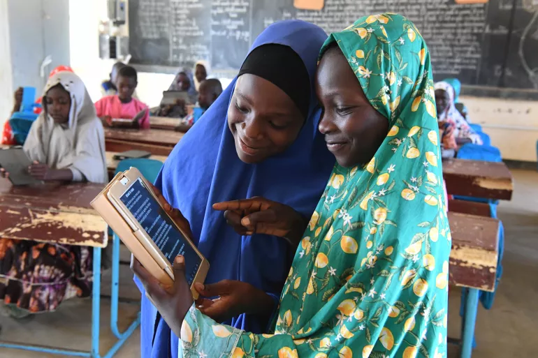 Two children attending class in school, looking at their tablets school.