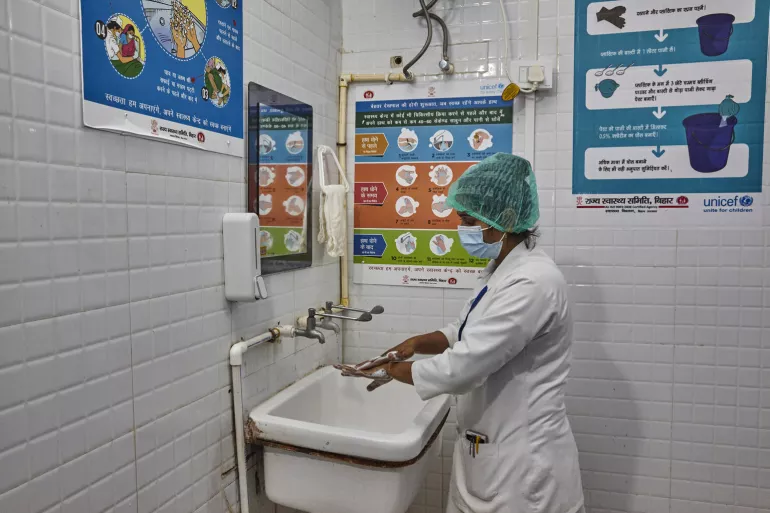 A nurse washing her hand with soap and water at a sink.
