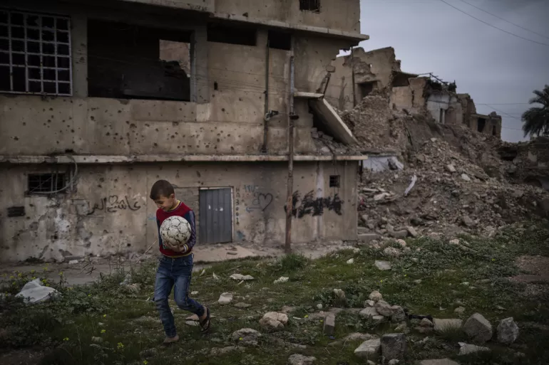 Iraq. A boy walks past a damaged building.