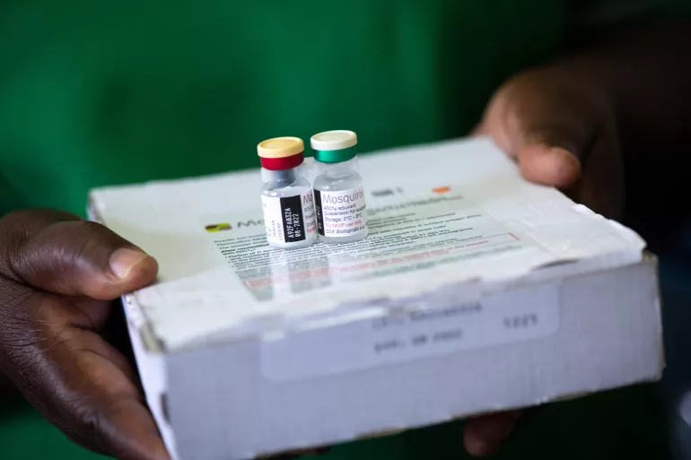 A pair of hands hold a box with two vaccine viales on it.