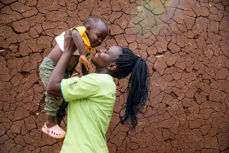 A woman lifts a child above her head.