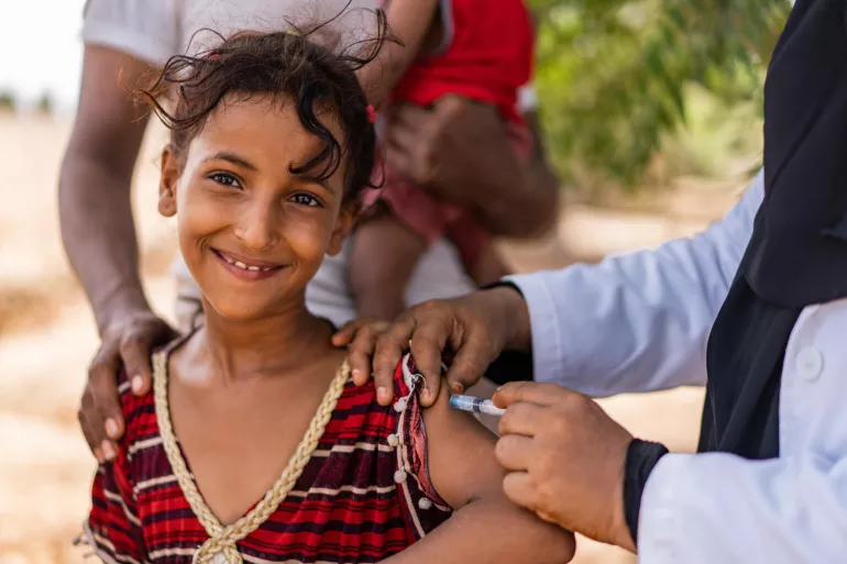 On 6 June 2022 in Aden Governorate, Yemen, health worker Ghada Ali Obaid, 53, vaccinates 11-year-old Amani Nasr during a community outreach vaccination drive for children.