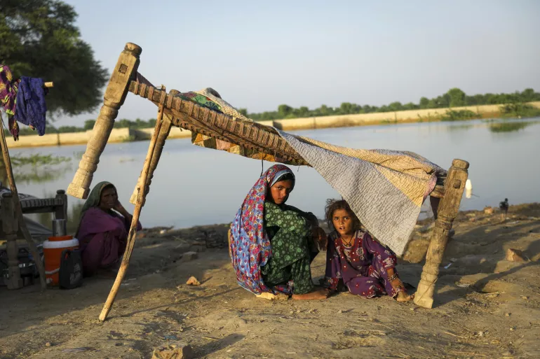 Pakistan. Families shelter by a river after flooding.