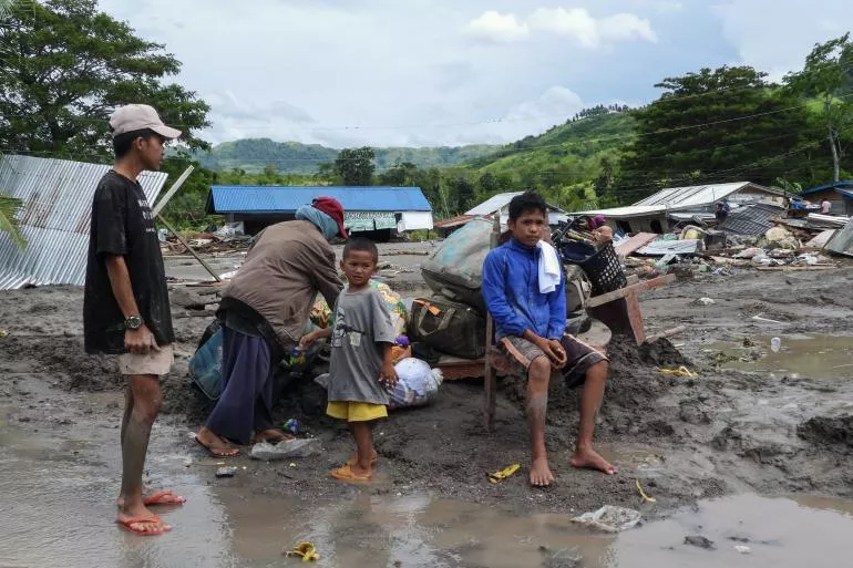 A family huddles together while standing in mud