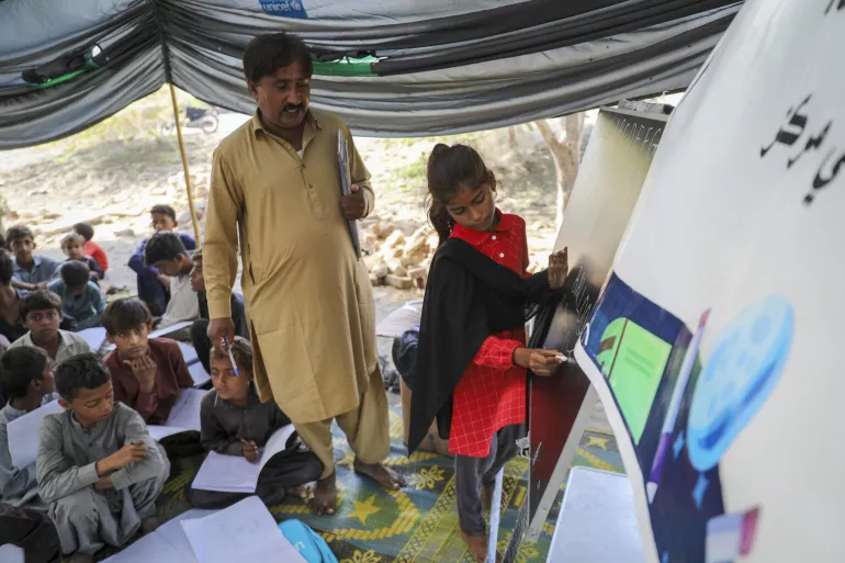 A student writes on a whiteboard in classroom based in a tent.
