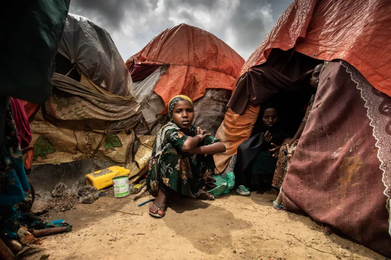 Una ni&ntilde;a sentada afuera de la tienda de campa&ntilde;a en la que vive su familia en un campamento para desplazados internos en Mogadiscio, Somalia, en octubre de 2022.