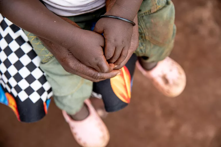 An adult pair of hands holds a child's pair of hands.