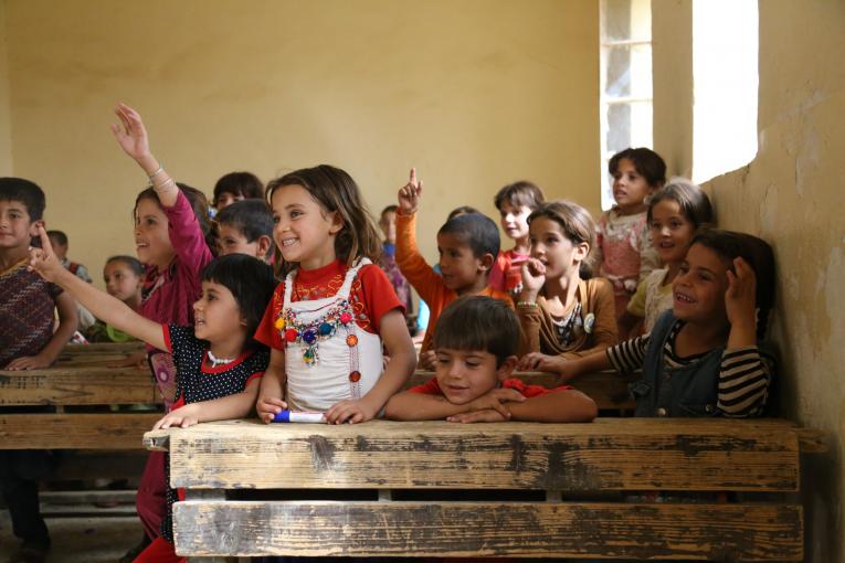 فتاة تقف بالقرب من طاولة في فصل دراسي، العراق